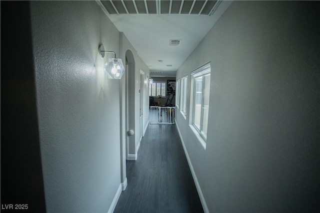 hall with baseboards, visible vents, and dark wood-style flooring