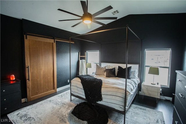 bedroom featuring visible vents, ceiling fan, a barn door, lofted ceiling, and wood finished floors