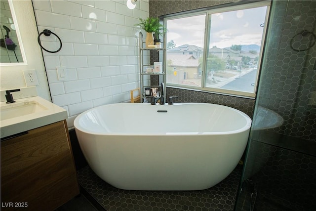 full bath with vanity, tile walls, and a freestanding tub