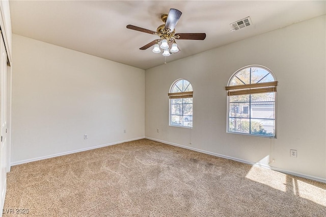 carpeted spare room with visible vents, baseboards, and a ceiling fan