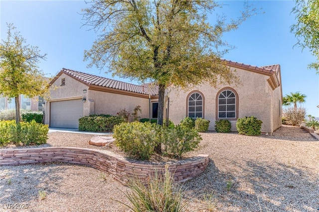 mediterranean / spanish home with stucco siding, a garage, and a tile roof