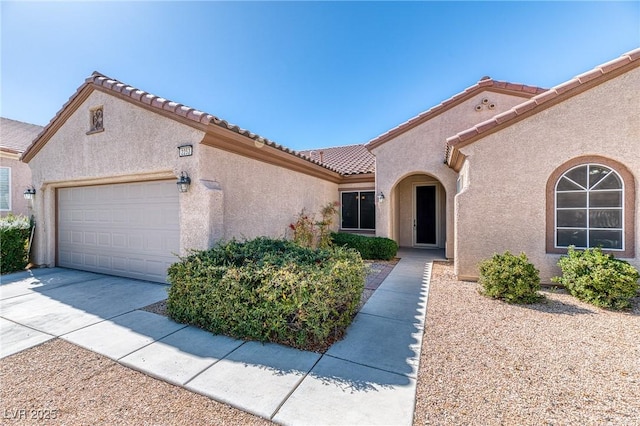 mediterranean / spanish-style house with a tiled roof, an attached garage, driveway, and stucco siding