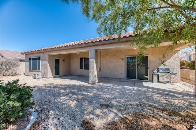 back of property with a tiled roof, a patio area, and stucco siding