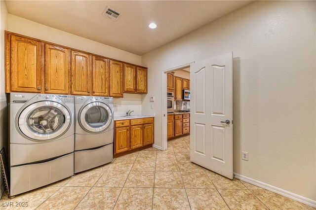 clothes washing area with light tile patterned floors, visible vents, cabinet space, a sink, and washing machine and dryer