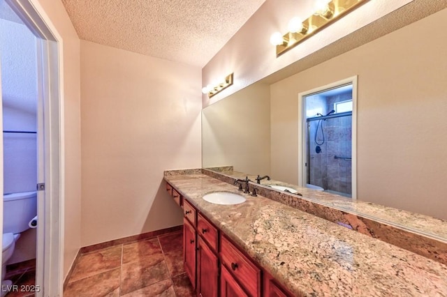 bathroom with baseboards, tiled shower, toilet, a textured ceiling, and vanity