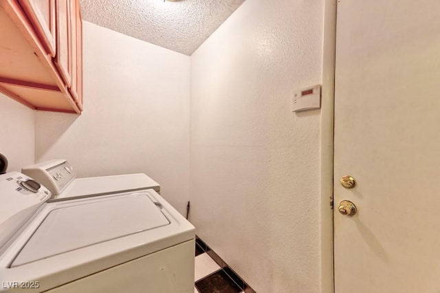 clothes washing area with cabinet space, washing machine and dryer, and a textured ceiling