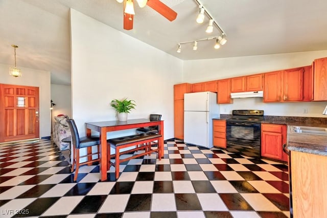 kitchen featuring under cabinet range hood, electric range, a sink, freestanding refrigerator, and dark countertops