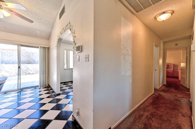 hall with arched walkways, visible vents, a textured ceiling, and tile patterned floors