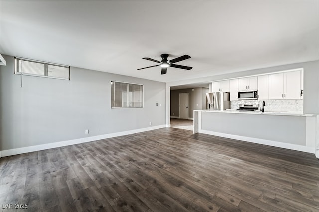 unfurnished living room with baseboards, visible vents, dark wood finished floors, and a ceiling fan