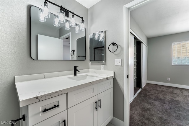 bathroom with a textured wall, baseboards, and vanity