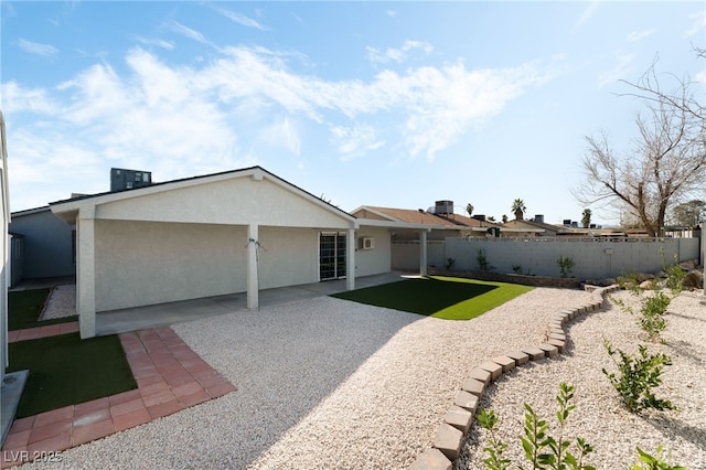 rear view of property featuring a patio area, a fenced backyard, and stucco siding