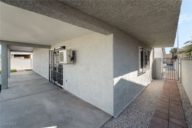 view of side of property with a gate, fence, and stucco siding