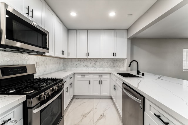 kitchen with marble finish floor, stainless steel appliances, decorative backsplash, white cabinetry, and a sink