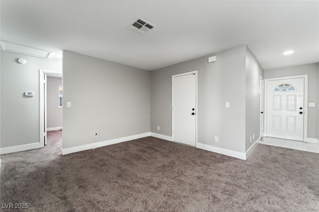 unfurnished room with visible vents, dark carpet, and baseboards