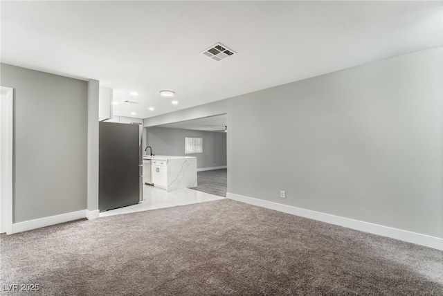 empty room featuring baseboards, visible vents, light colored carpet, a sink, and recessed lighting