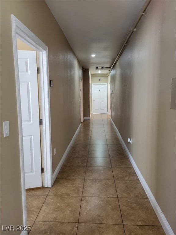 corridor featuring tile patterned flooring and baseboards