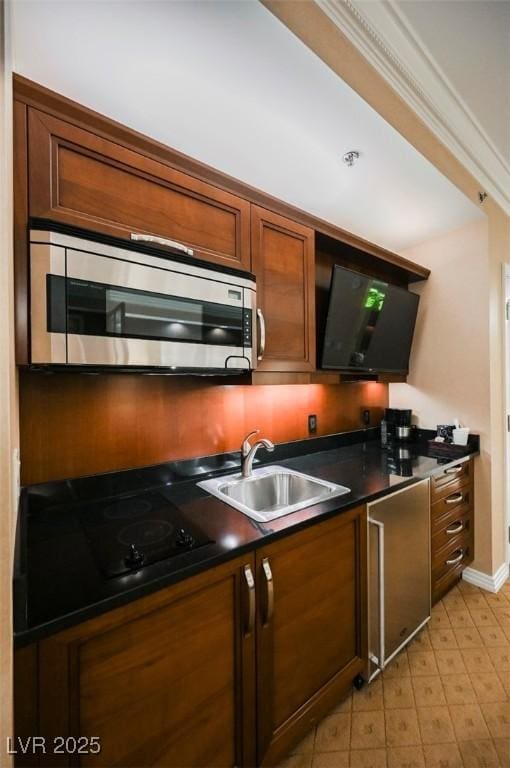 kitchen featuring black electric stovetop, a sink, stainless steel microwave, dark countertops, and crown molding