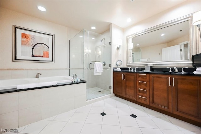 bathroom with double vanity, a stall shower, a bath, a sink, and recessed lighting