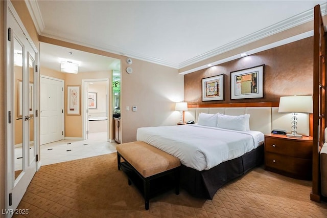 bedroom featuring ensuite bath, baseboards, and crown molding