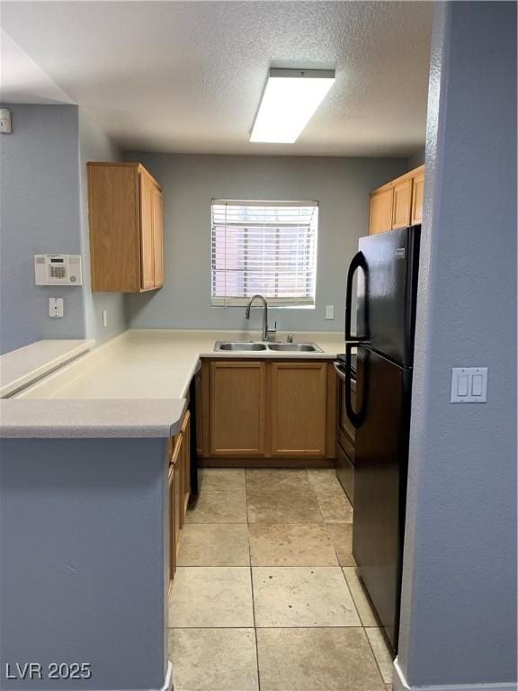 kitchen featuring light countertops, stove, a sink, and freestanding refrigerator