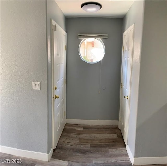 interior space featuring a textured wall, baseboards, and wood finished floors