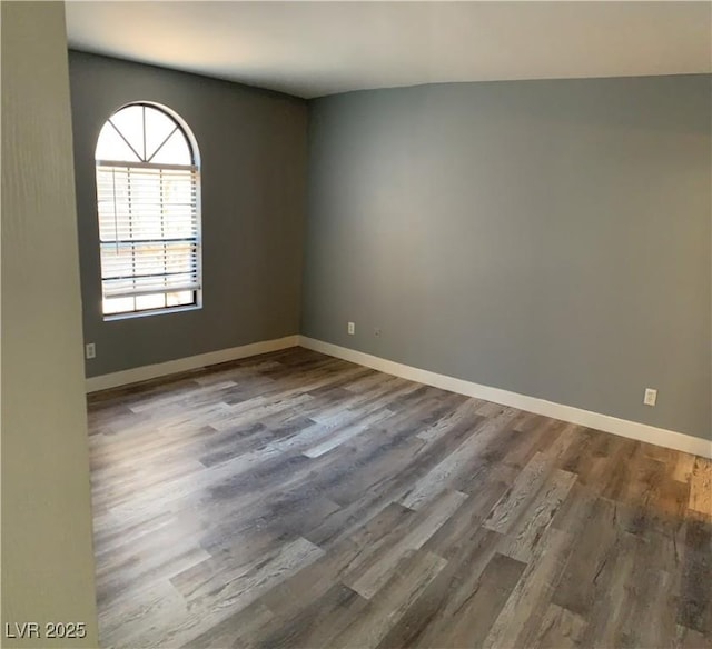 unfurnished room with dark wood-style flooring and baseboards