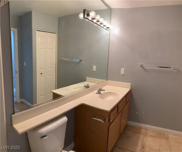 bathroom with toilet, vanity, and baseboards