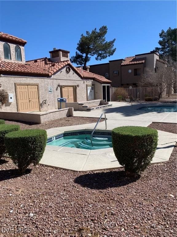 rear view of property with a patio, a community pool, fence, a tiled roof, and stucco siding