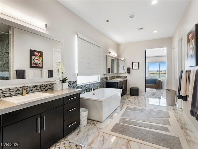 ensuite bathroom with tasteful backsplash, marble finish floor, ensuite bath, and a sink