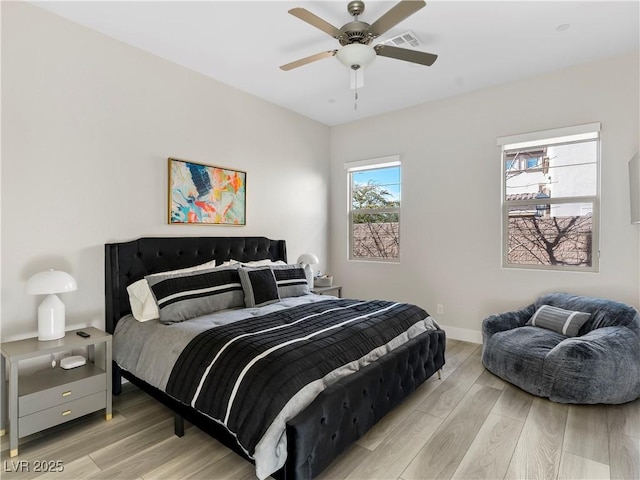 bedroom with visible vents, light wood-style floors, baseboards, and ceiling fan