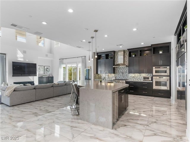 kitchen with a kitchen breakfast bar, open floor plan, wall chimney exhaust hood, and marble finish floor