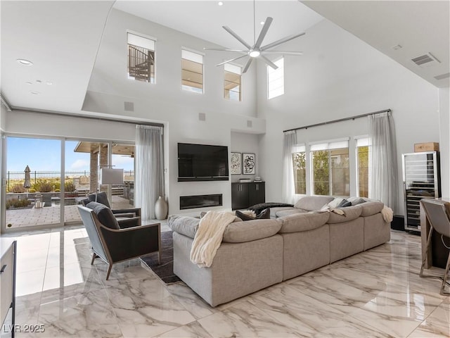 living room with visible vents, marble finish floor, a ceiling fan, and a glass covered fireplace