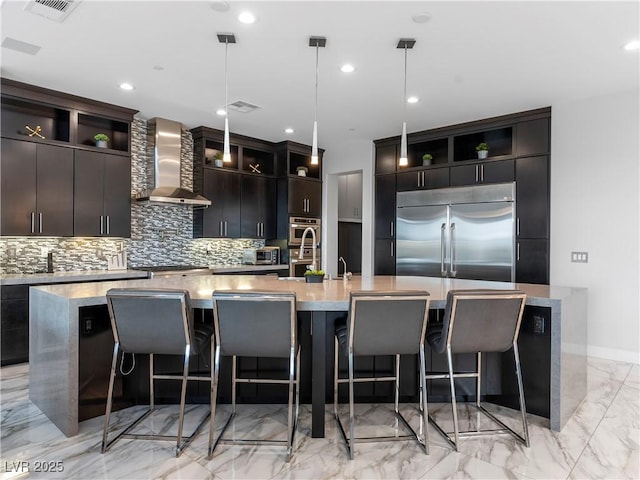 kitchen featuring open shelves, wall chimney exhaust hood, a large island with sink, and stainless steel appliances