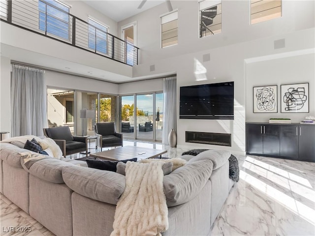 living area with a glass covered fireplace, a high ceiling, and marble finish floor