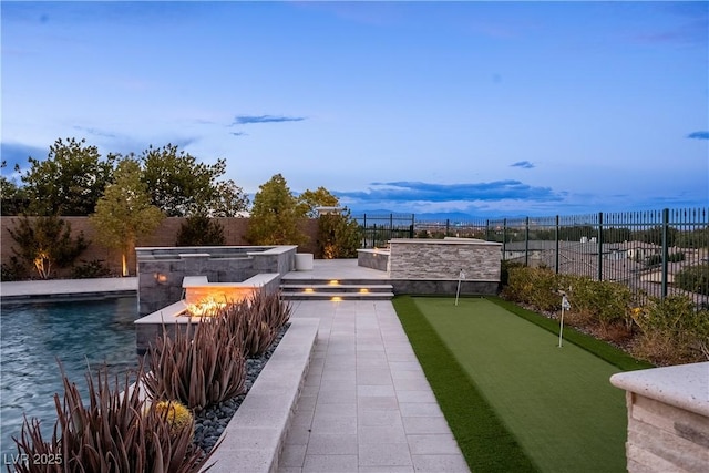 view of community with a fenced backyard and a fire pit