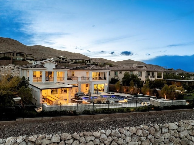 rear view of property featuring a patio area, a balcony, a fenced backyard, and a mountain view