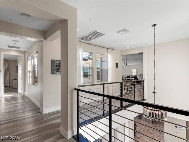 corridor featuring visible vents, an upstairs landing, baseboards, and wood finished floors