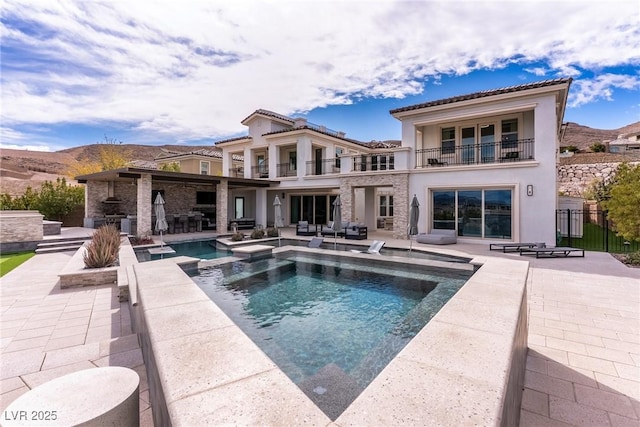 rear view of house featuring fence, stucco siding, outdoor lounge area, a balcony, and a patio