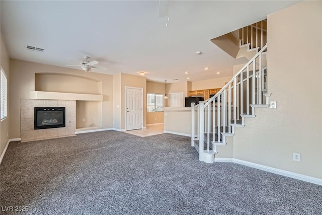 unfurnished living room featuring baseboards, visible vents, ceiling fan, carpet flooring, and a fireplace