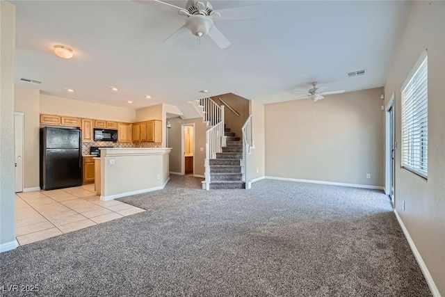 unfurnished living room featuring a ceiling fan, stairway, visible vents, and light colored carpet