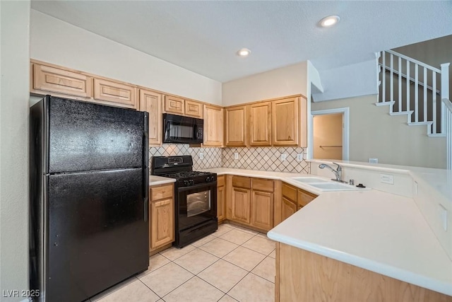 kitchen featuring light tile patterned floors, a peninsula, a sink, black appliances, and backsplash