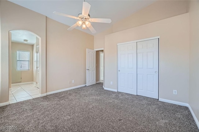 unfurnished bedroom with baseboards, a closet, arched walkways, and carpet flooring