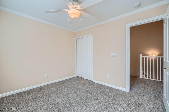 unfurnished bedroom featuring carpet, a closet, baseboards, and crown molding