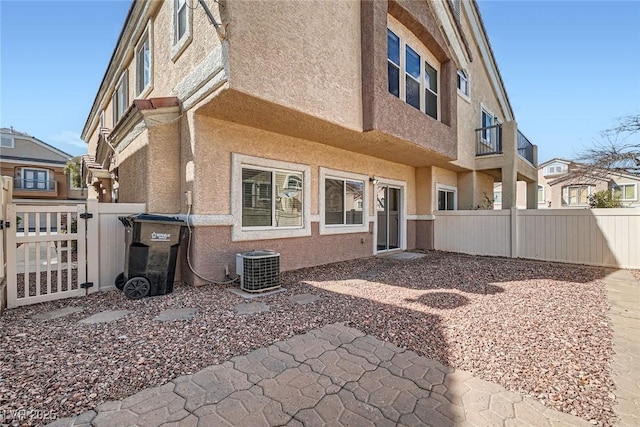 rear view of house featuring cooling unit, a fenced backyard, and stucco siding