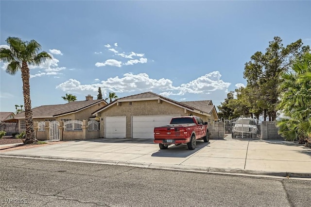 view of front of home with a garage, concrete driveway, a gate, fence, and stucco siding