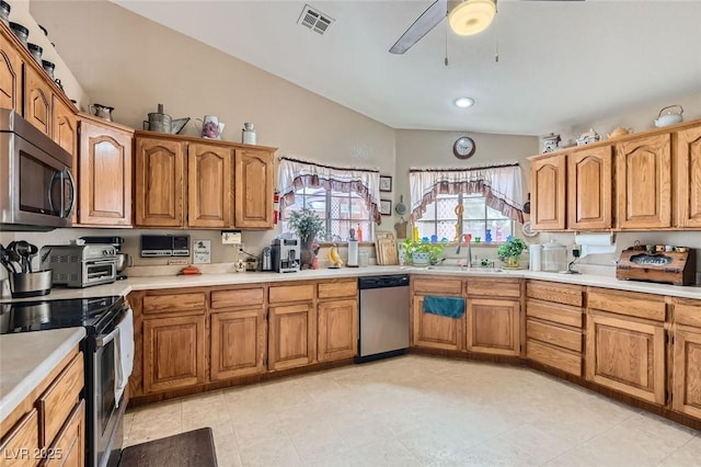 kitchen featuring lofted ceiling, a sink, visible vents, light countertops, and appliances with stainless steel finishes