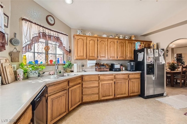 kitchen with vaulted ceiling, light countertops, a sink, and stainless steel fridge with ice dispenser