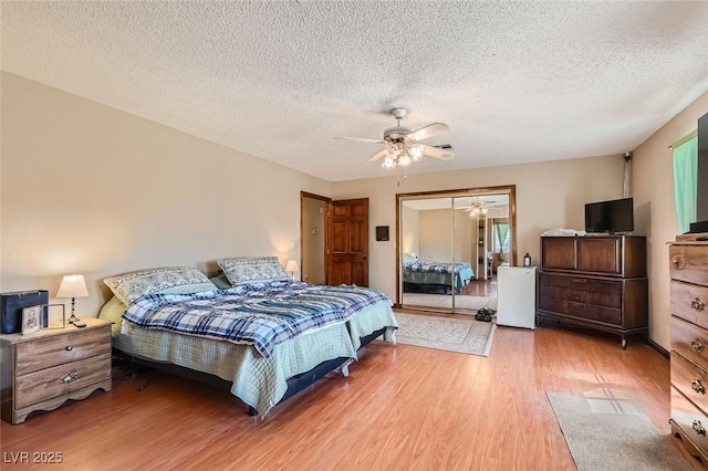 bedroom with light wood finished floors, a textured ceiling, a ceiling fan, and a closet