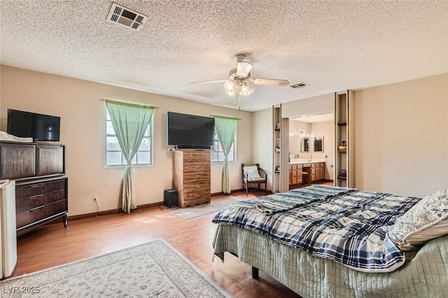 bedroom featuring ceiling fan, wood finished floors, visible vents, and baseboards