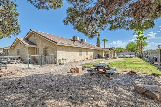 rear view of property featuring a gate, stucco siding, fence, and central air condition unit